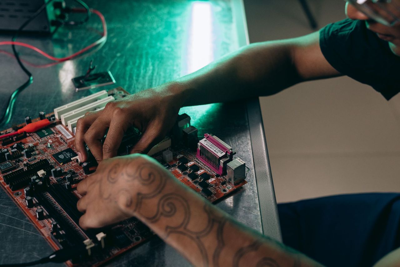 Hands working on a computer motherboard at a bench