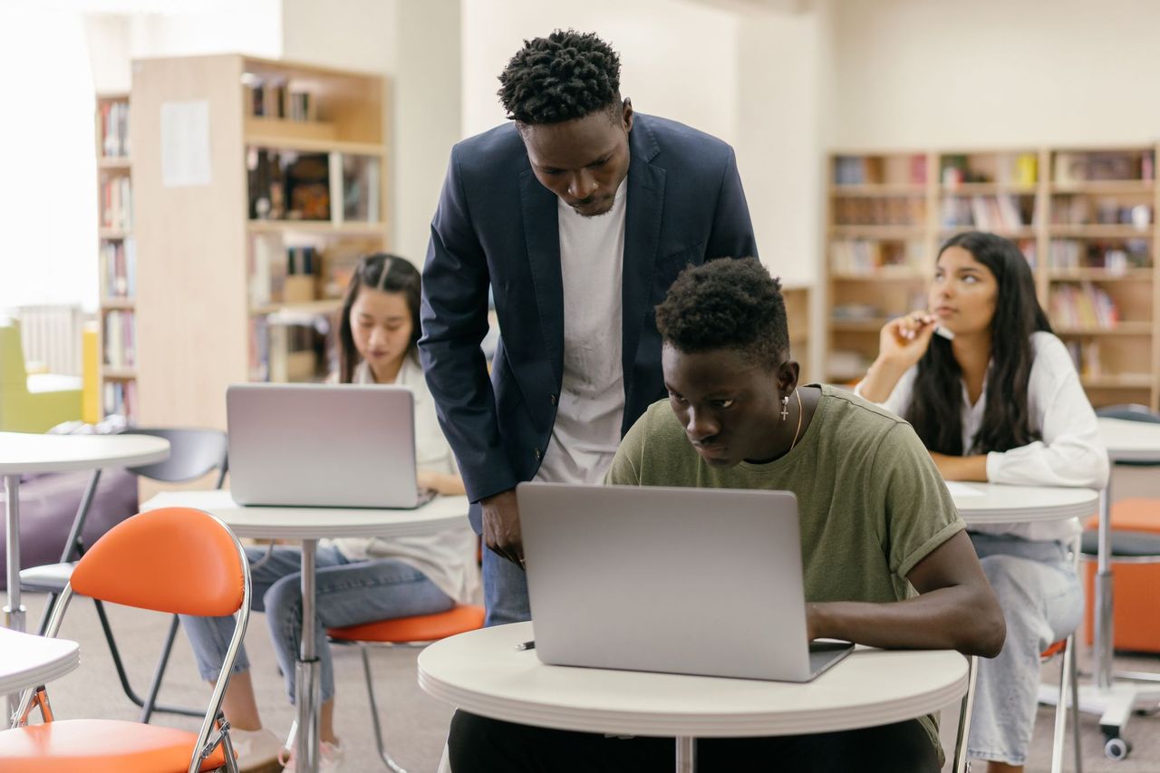 Teacher helping a student on a laptop