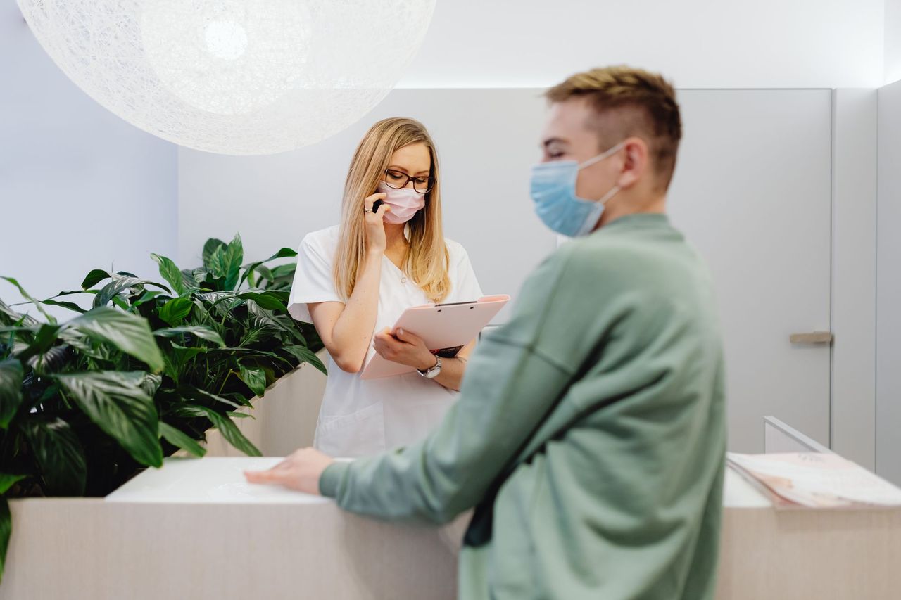 Front desk staff helping a patient at a clinic