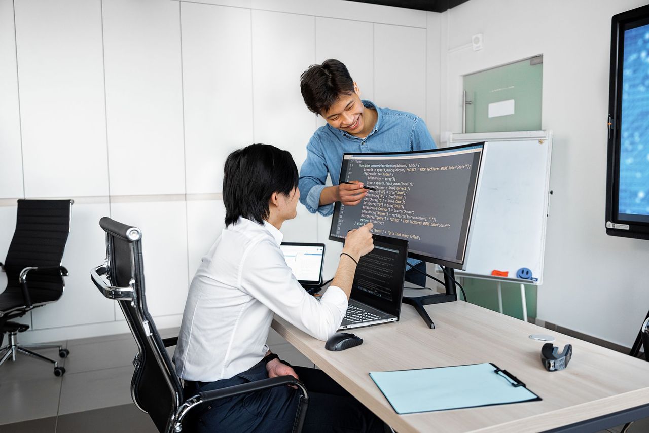 Two developers reviewing work on a monitor